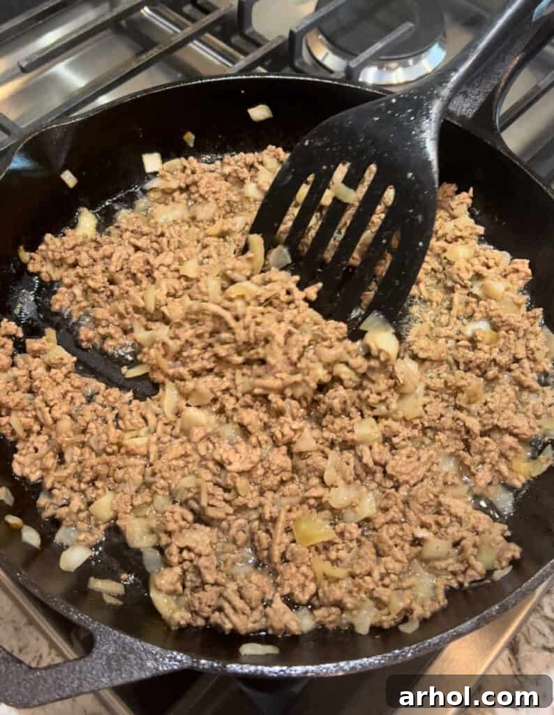 Quick One-Pot Cheesy Taco Pasta 4 Sautéing ground beef and diced onion in a cast iron skillet until beef is browned.