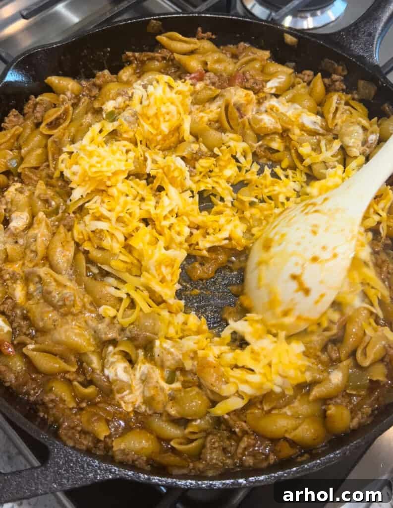 Quick One-Pot Cheesy Taco Pasta 6 Stirring in shredded cheese and sour cream into the cooked taco pasta mixture in the skillet.