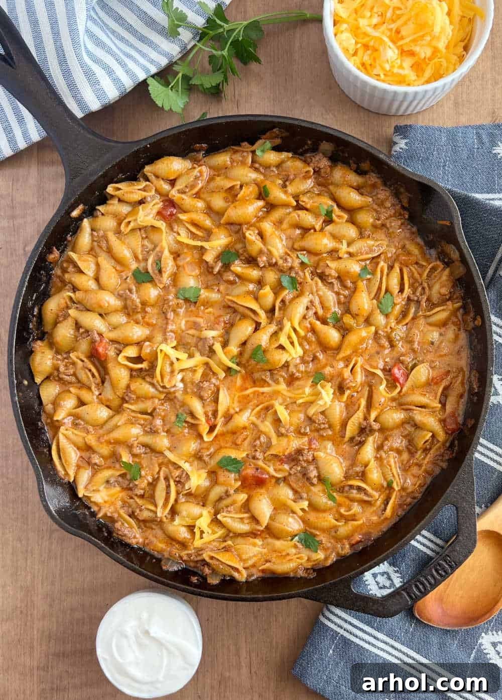 Quick One-Pot Cheesy Taco Pasta 7 A large cast iron skillet filled with cheesy taco pasta, garnished and ready to serve on a table setting.