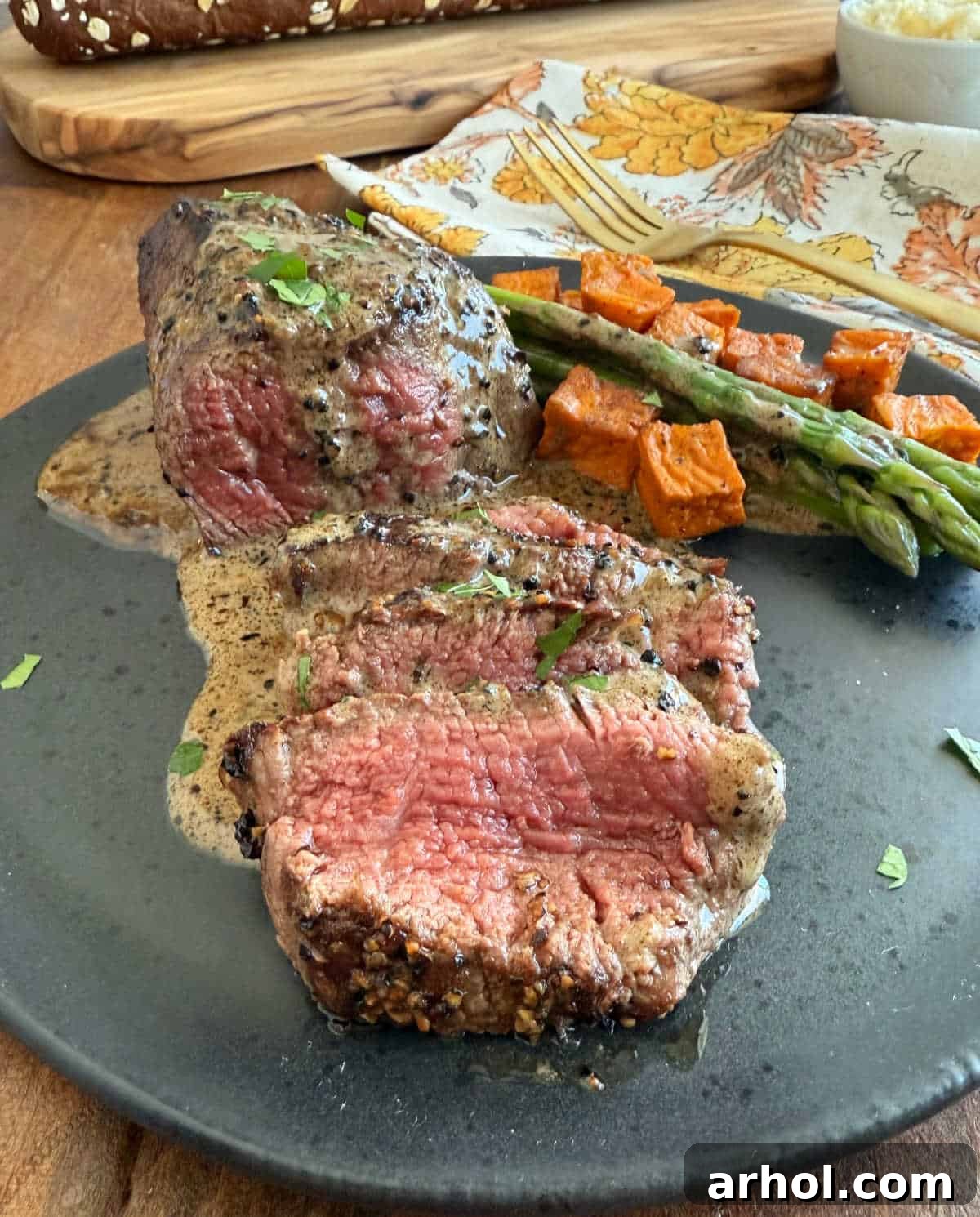 Effortless Peppercorn Steak 2 Sliced steak au poivre in bourbon cream sauce on a plate with fresh vegetables, ready to serve.