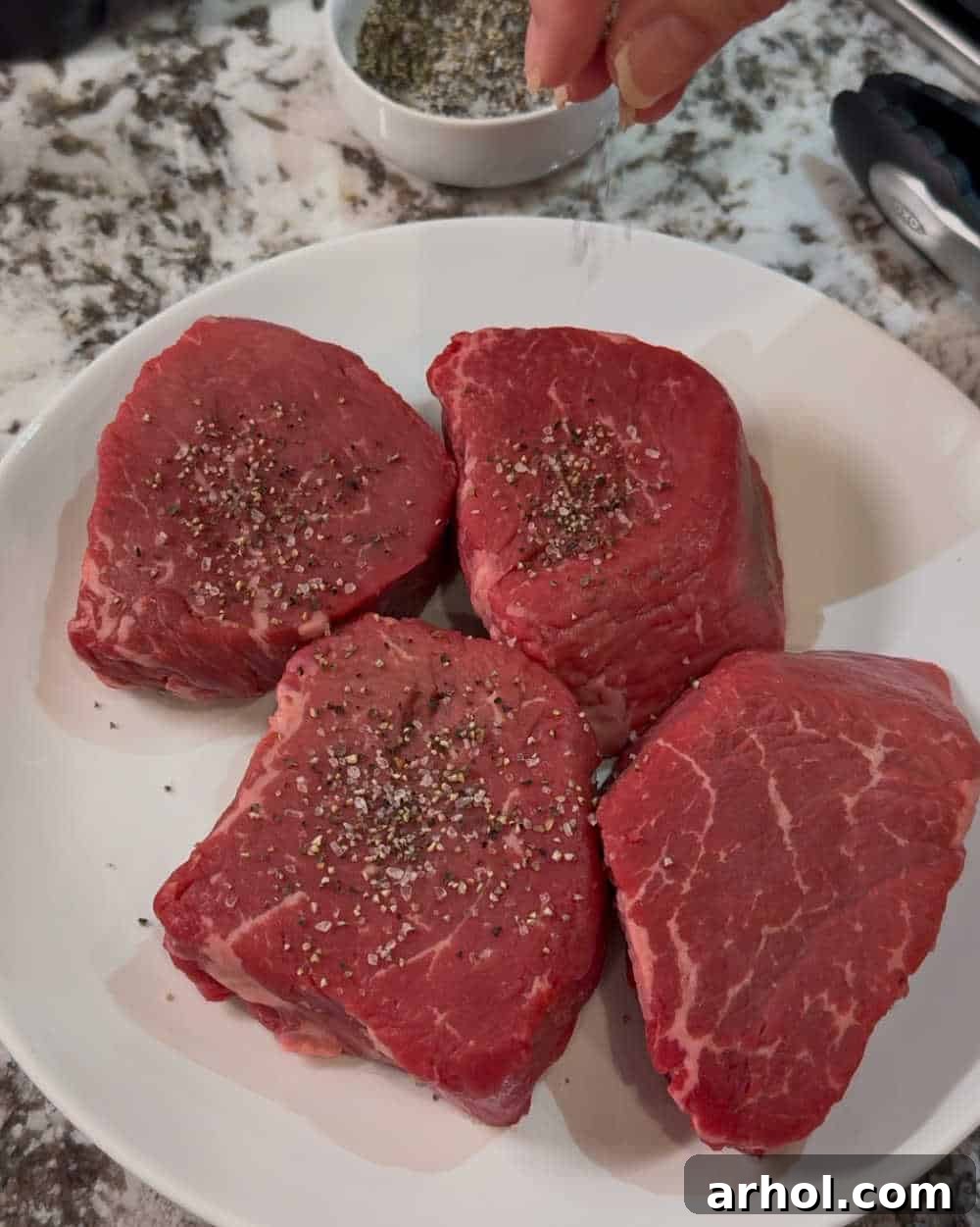 Effortless Peppercorn Steak 4 Seasoning beef filets with coarse pepper and salt on a cutting board.