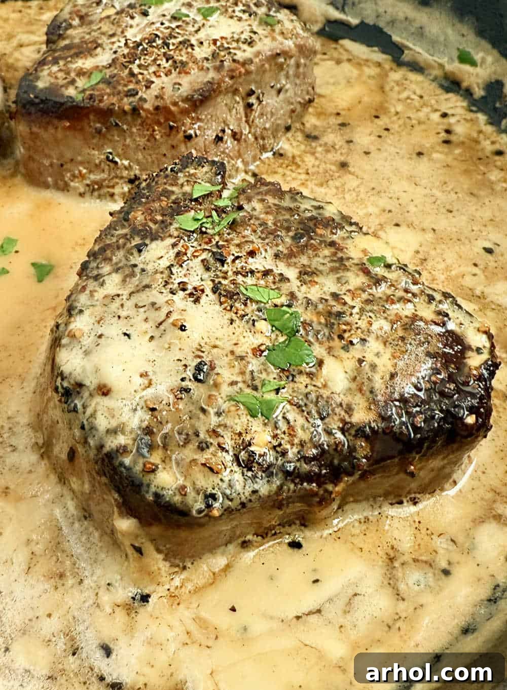 Effortless Peppercorn Steak 8 Steak au poivre in a skillet with creamy bourbon sauce, garnished with fresh herbs.