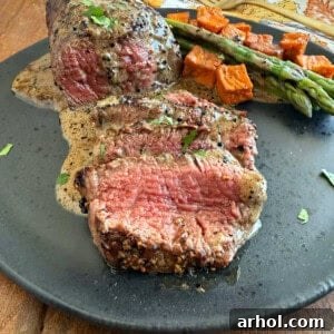Sliced steak au poivre in bourbon sauce on a plate, garnished with fresh parsley.