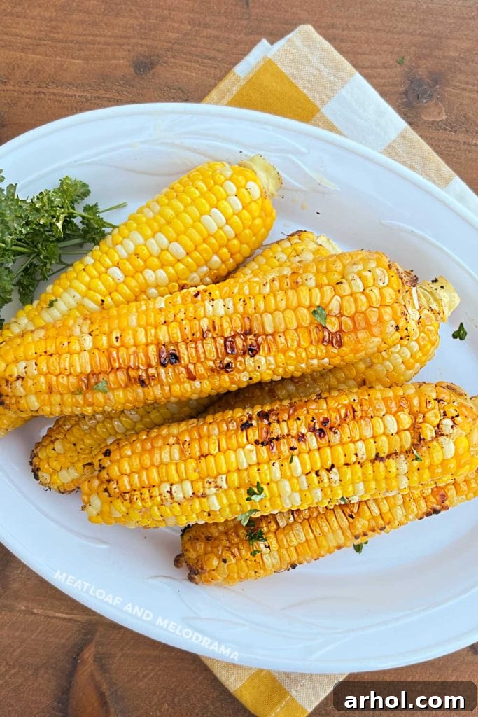 Foil grilled corn on a white serving platter with parsley