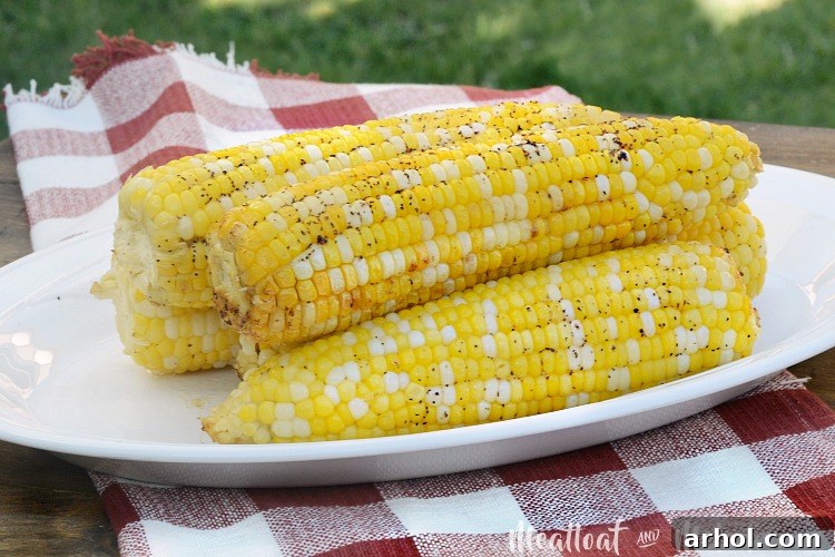 Foil grilled corn on the cob on platter in backyard