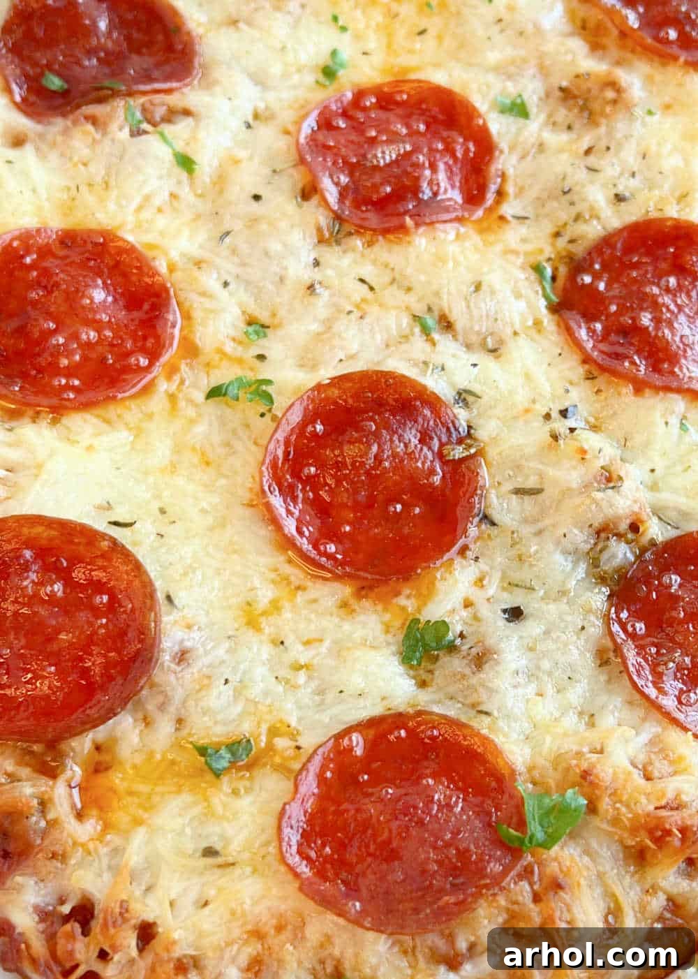A close-up of the baked pizza pasta casserole, showcasing the bubbly melted cheese and perfectly crisped pepperoni slices.