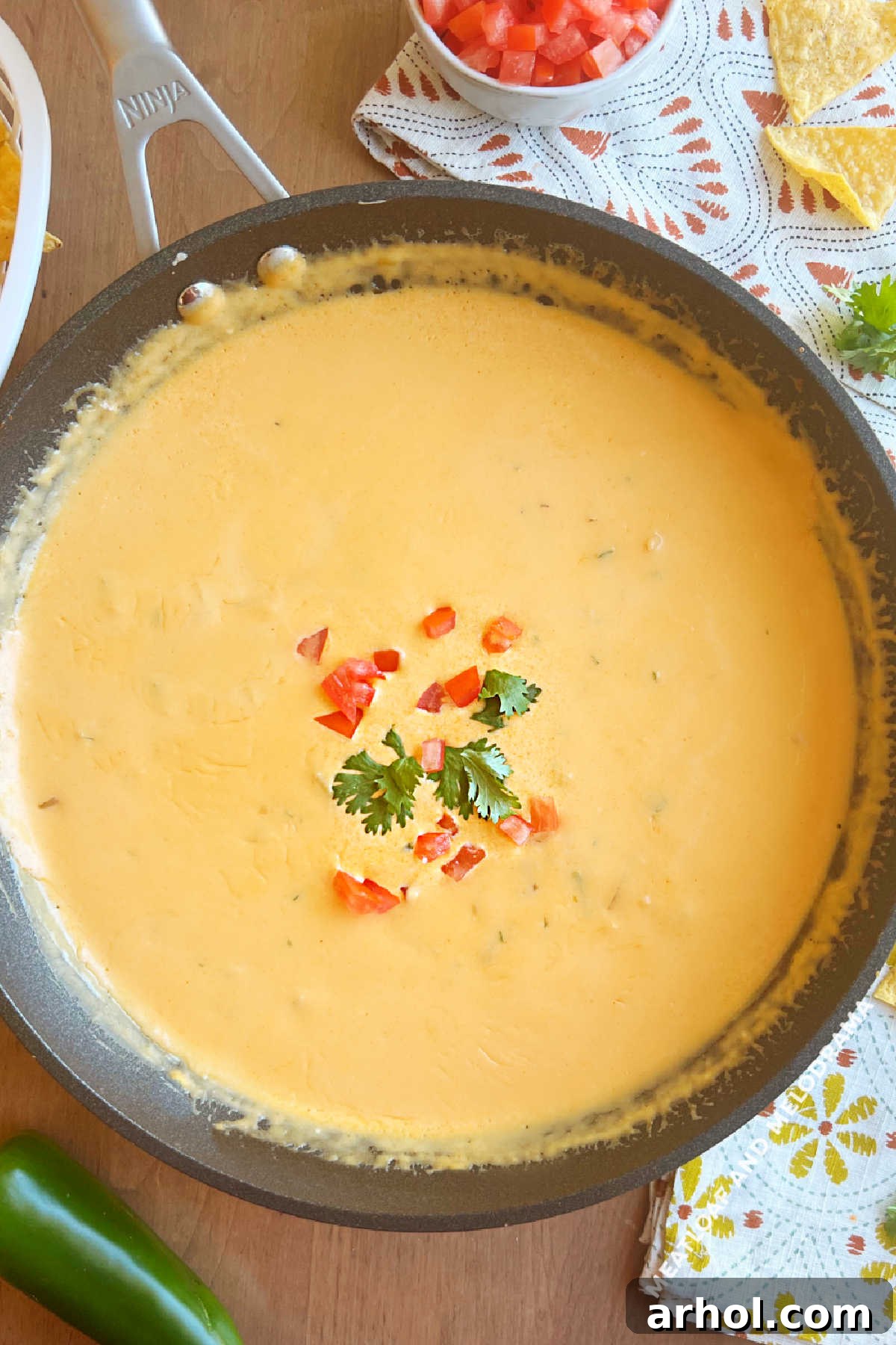 Rich, golden homemade queso dip, made without Velveeta, served in a cast iron skillet with fresh cilantro garnish, ready for dipping with tortilla chips.