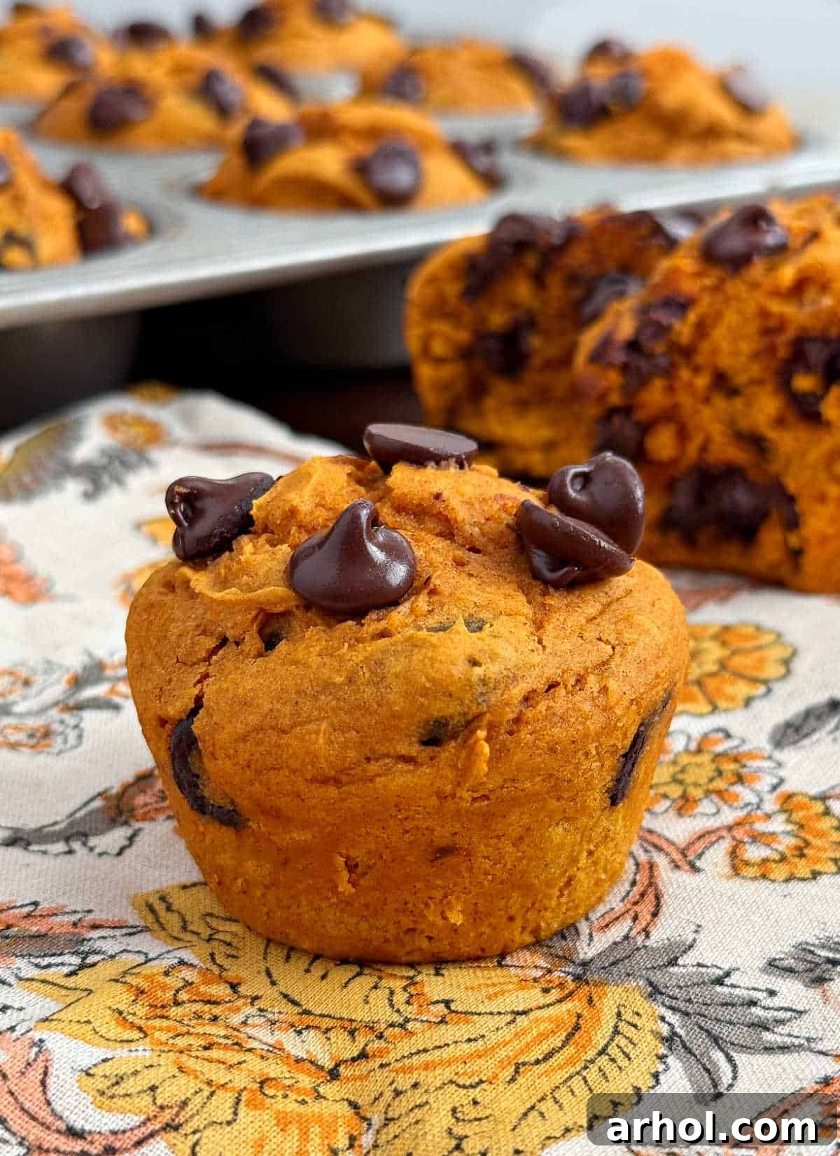 Golden cake mix pumpkin muffins with melted chocolate chips on a rustic wooden table, ready to be enjoyed.