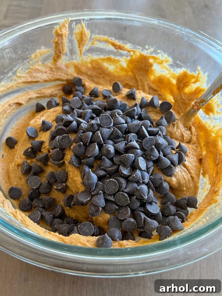 The thick muffin batter in a mixing bowl, showcasing the combined cake mix, pumpkin puree, and chocolate chips.