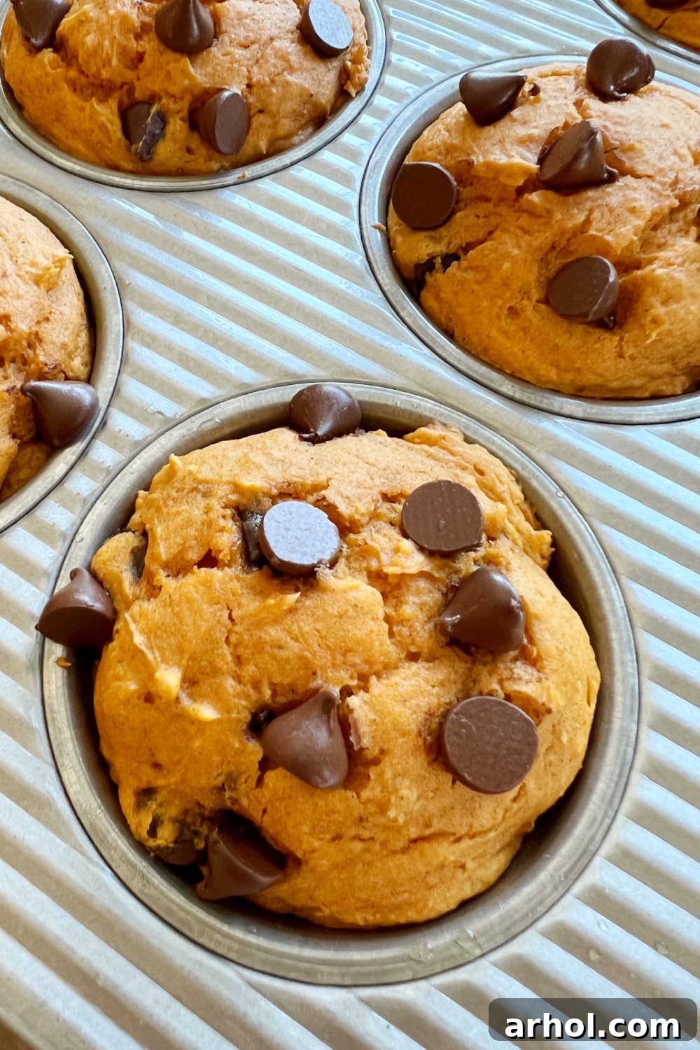 Freshly baked cake mix pumpkin muffins still in the muffin tin, cooling slightly after being removed from the oven.