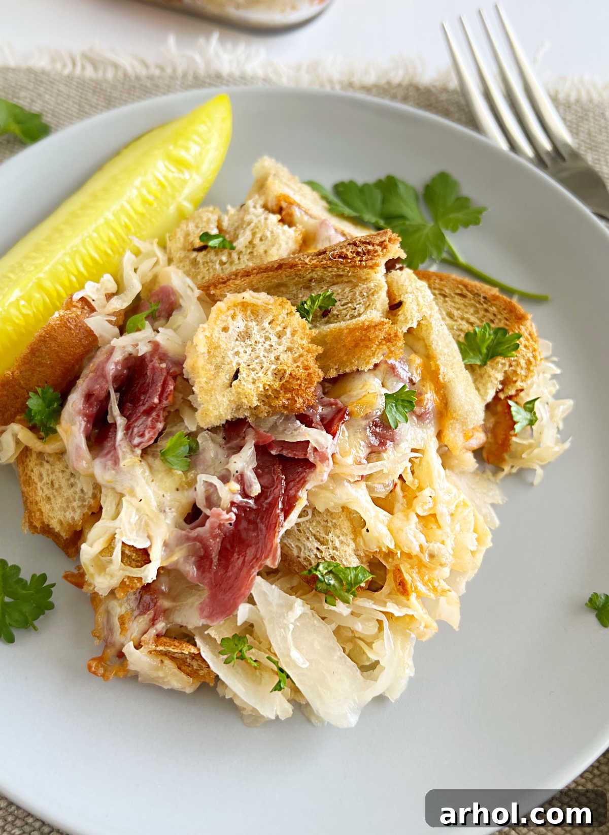 Reuben casserole with corned beef and sauerkraut on a plate with pickle.