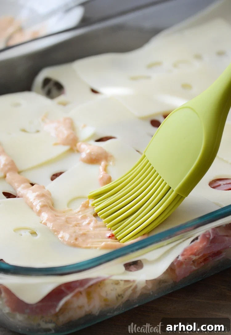 Thousand Island dressing spread over Swiss cheese in a casserole dish.