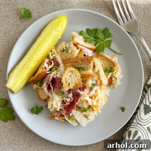 Baked Reuben casserole with corned beef and sauerkraut on a plate with a pickle