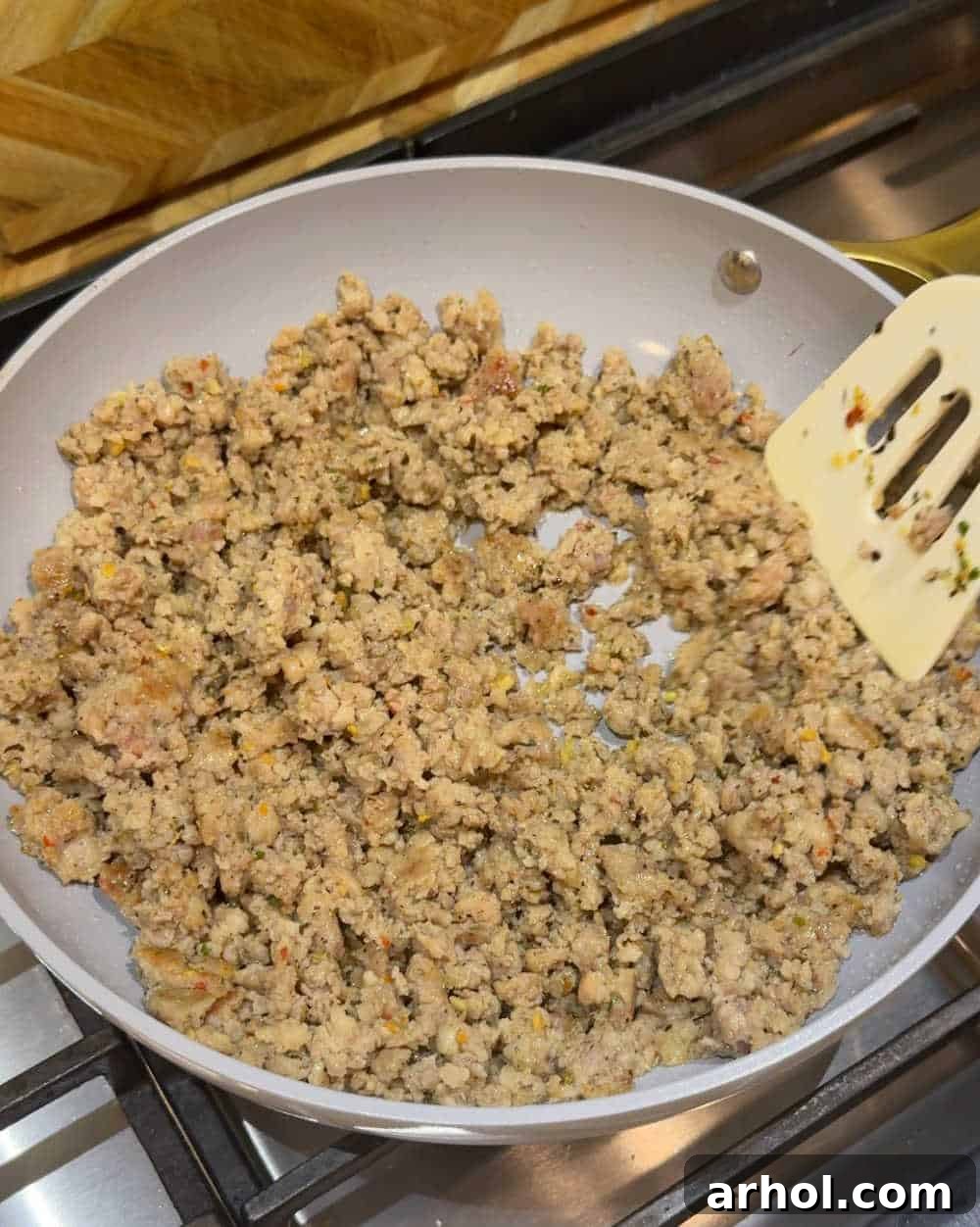 Cooking breakfast sausage in a non-stick skillet, crumbling it evenly.