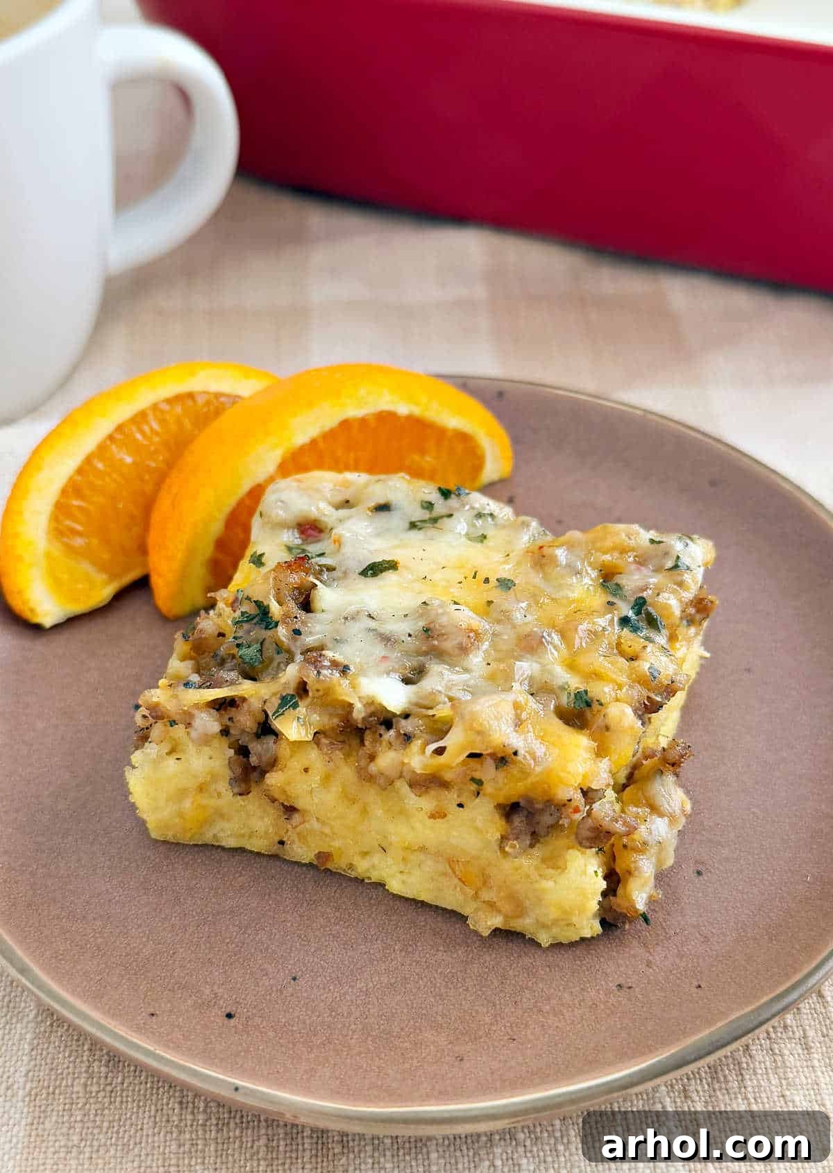 A perfectly baked slice of sausage egg breakfast casserole on a white plate, showing the layers of sourdough, sausage, and melted cheese.