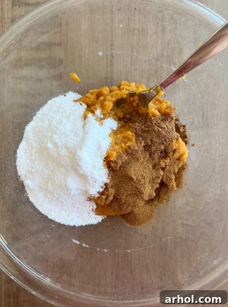 Creamy No-Bake Pumpkin Pie Dip: Your Effortless Fall Treat 4 Instant vanilla pudding mix, pumpkin puree, and a blend of spices are seen mixed together in a large mixing bowl, creating a rich orange base for the dip.