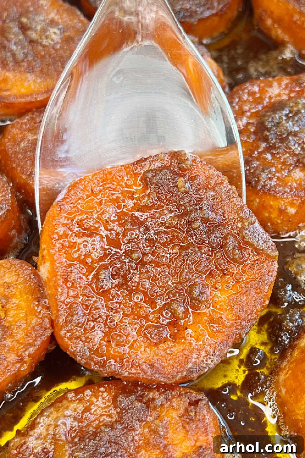 Candied yams with brown sugar glaze served on a spoon