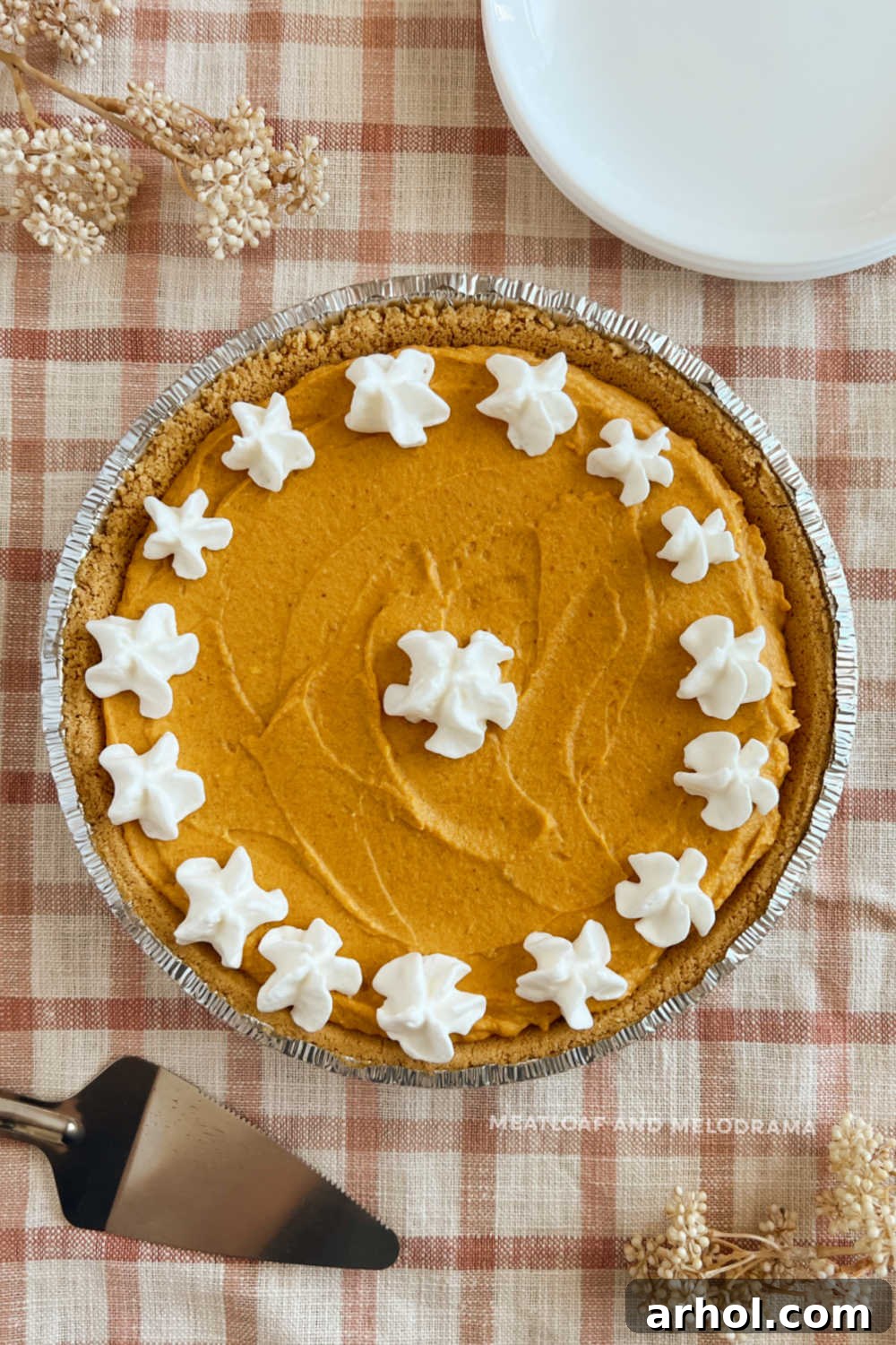 Delicious slice of No-Bake Pumpkin Cheesecake Pie with a creamy filling and graham cracker crust, topped with a dollop of whipped cream, ready to be served for Thanksgiving dinner.