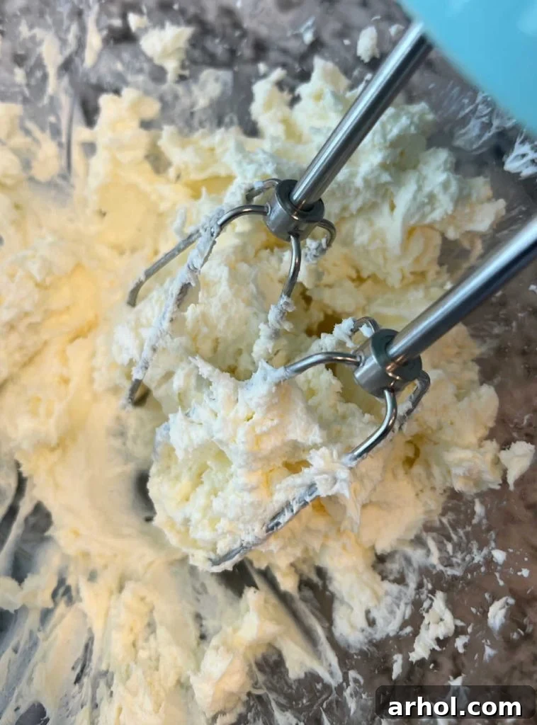 Creaming softened butter and cream cheese together in a mixing bowl using an electric mixer until light and fluffy.
