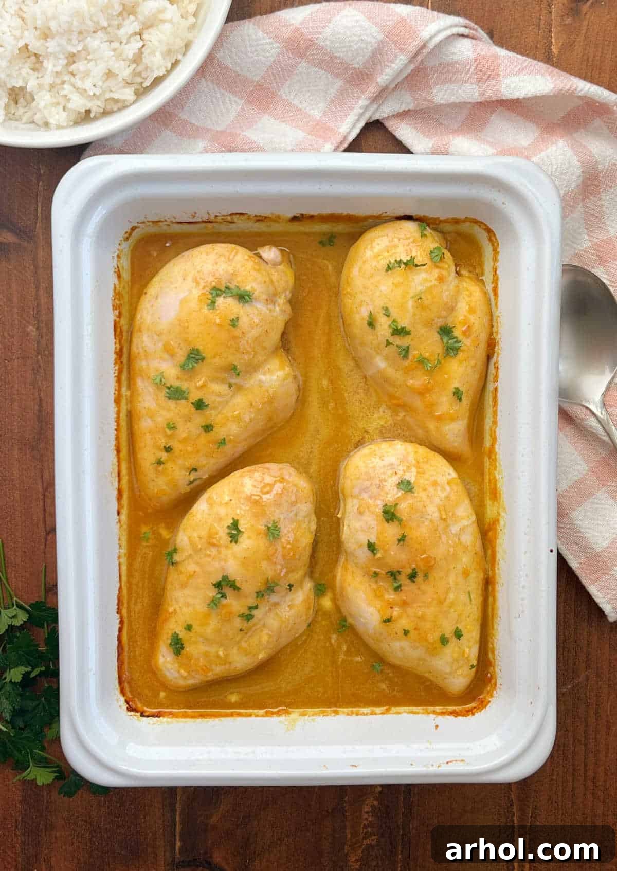 Baked honey mustard curry chicken served with rice on a rustic table.