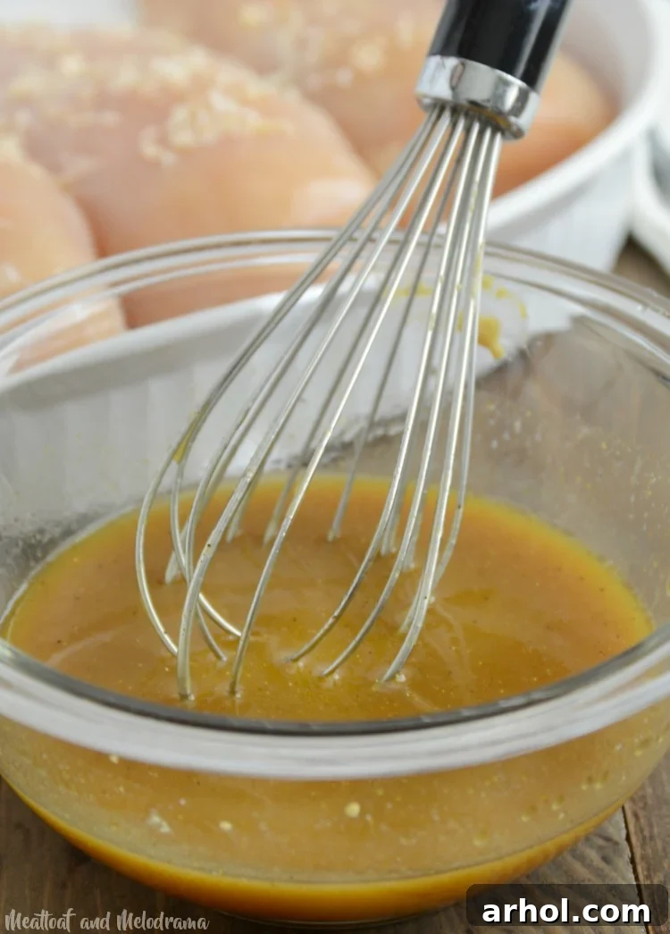 Whisking the sweet and savory sauce for honey mustard curry chicken in a bowl.