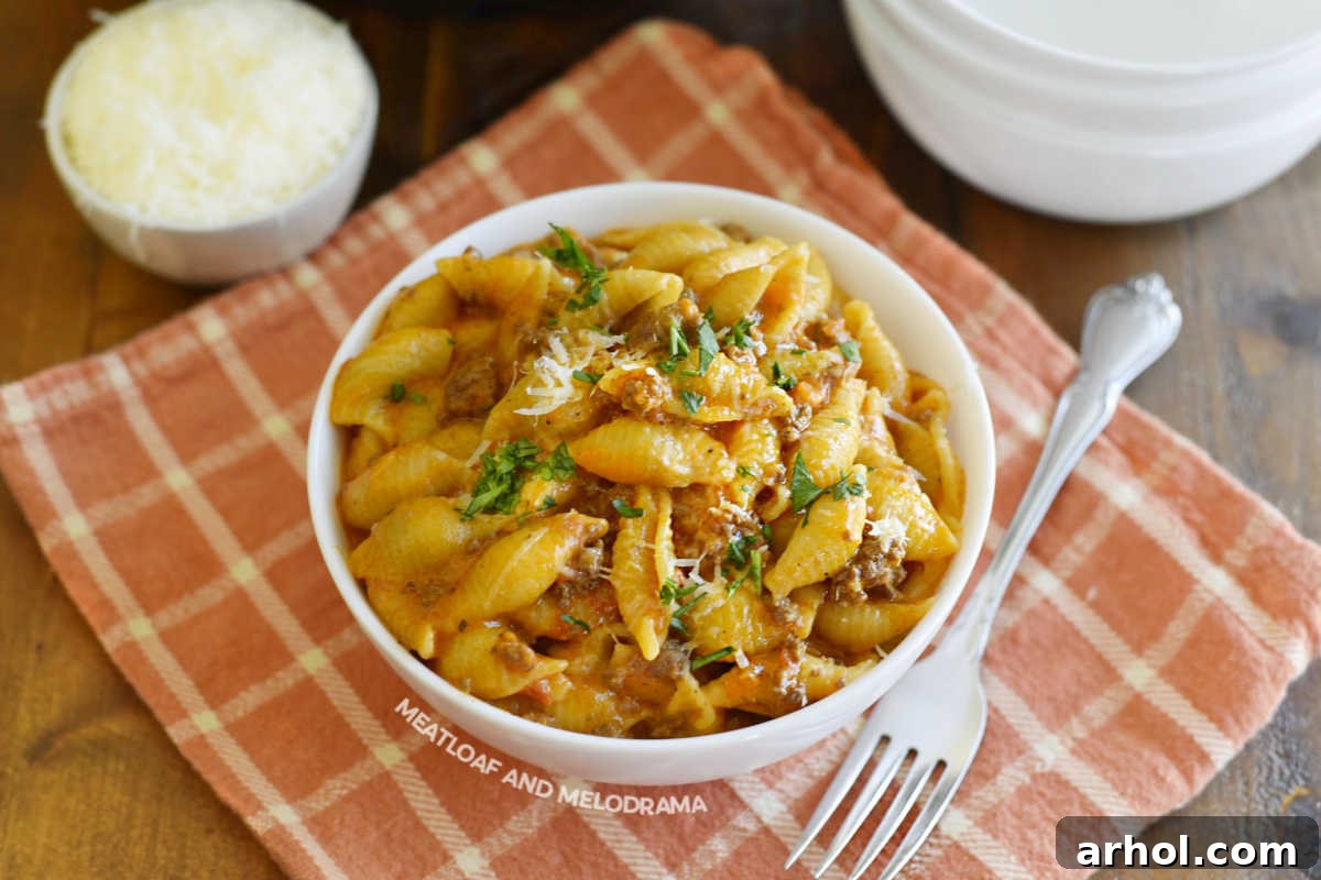 A serving of Instant Pot Creamy Shells and Beef on a white plate, garnished with fresh herbs.
