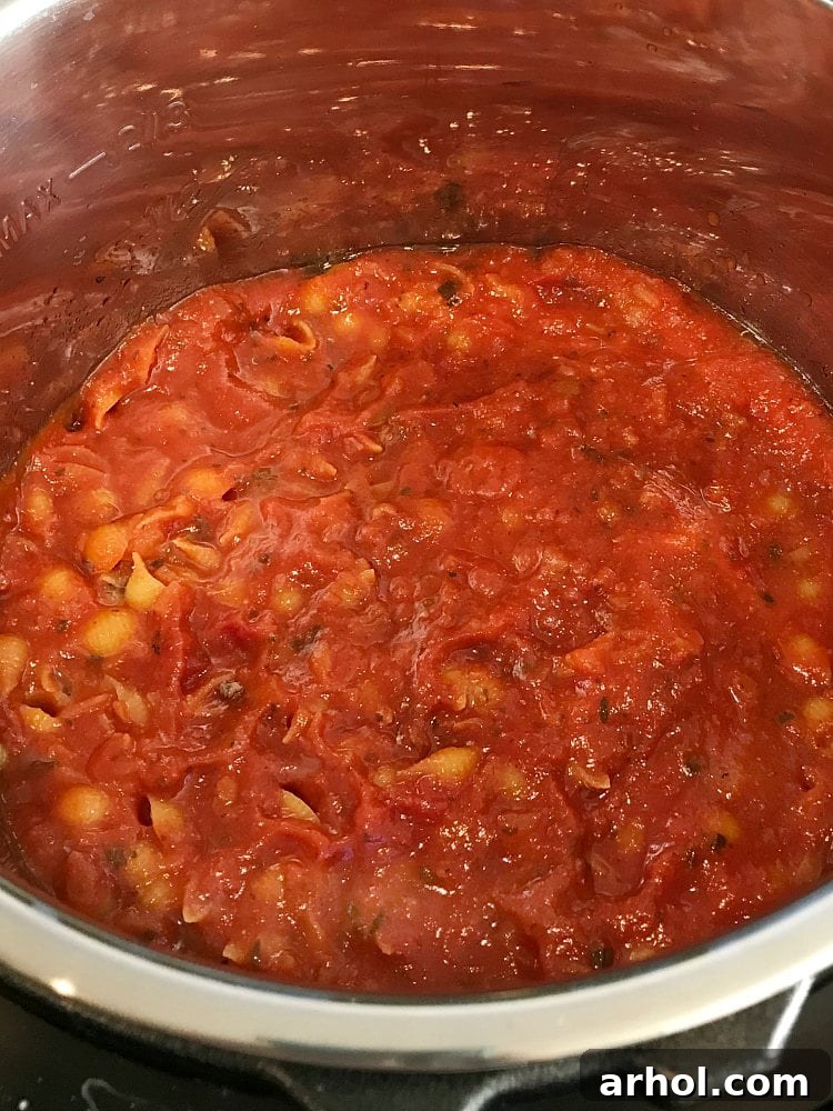 Uncooked pasta, ground beef, and sauce layered in an Instant Pot before pressure cooking.