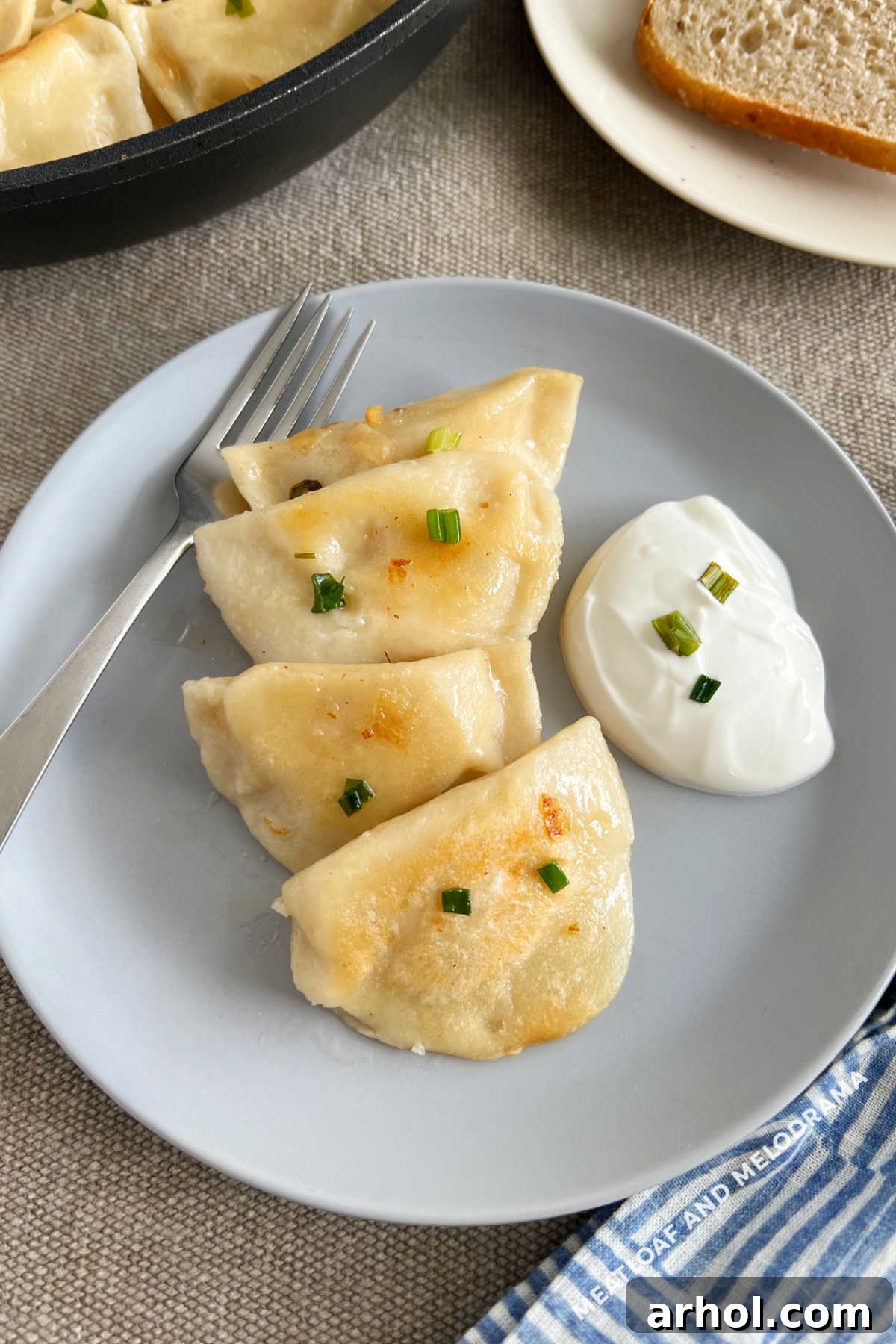 homemade pierogi with caramelized onions and sour cream on a plate
