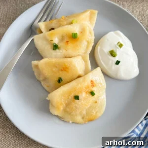 Homemade potato cheese pierogi on plate with sour cream