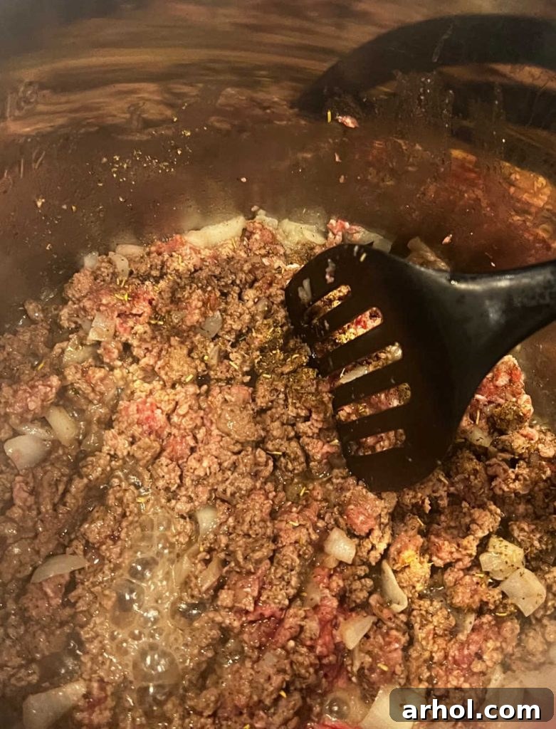 Browned ground beef, onions, and spices being cooked in an Instant Pot