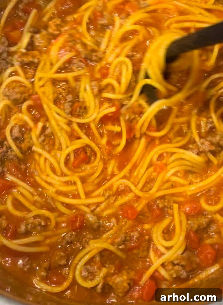 Stirring cooked spaghetti noodles and meat sauce in the Instant Pot after pressure release
