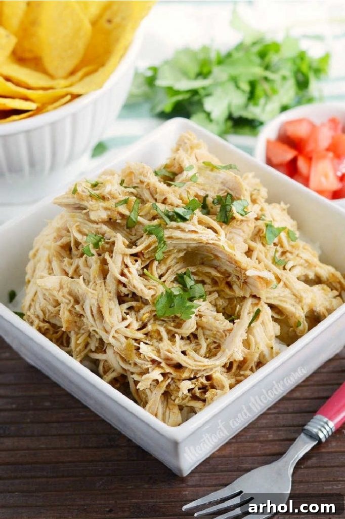 Generous serving of shredded salsa verde chicken in a white dish, garnished with fresh cilantro.