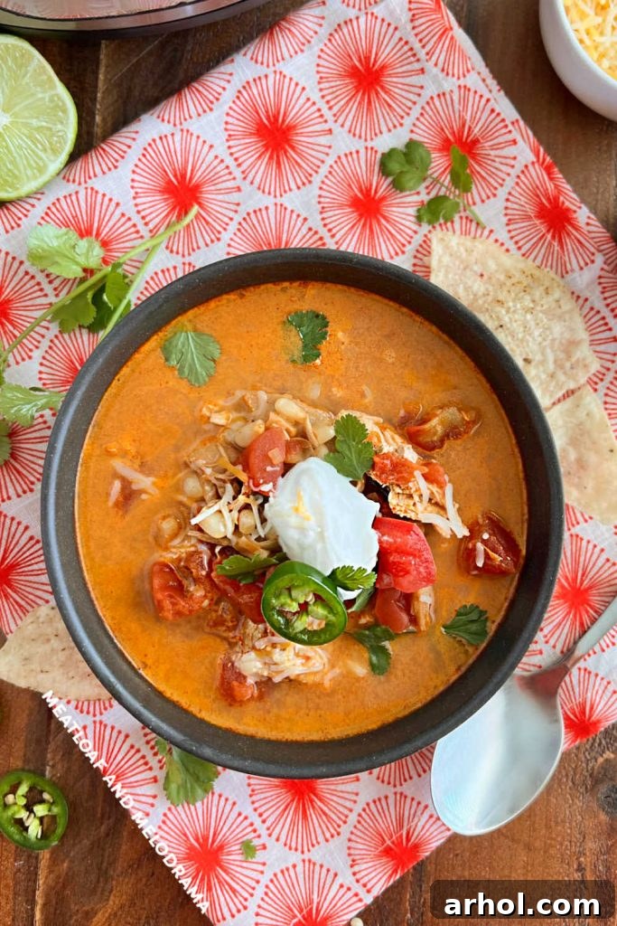 Instant Pot Chicken Enchilada Soup topped with sour cream, jalapeño slices, and fresh cilantro, served in a rustic bowl.