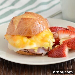 cheesy ham and egg breakfast sliders on plate with fruit