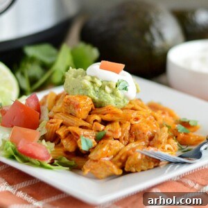 Instant Pot Chicken Enchilada Pasta on white plate with guacamole, sour cream, tomatoes