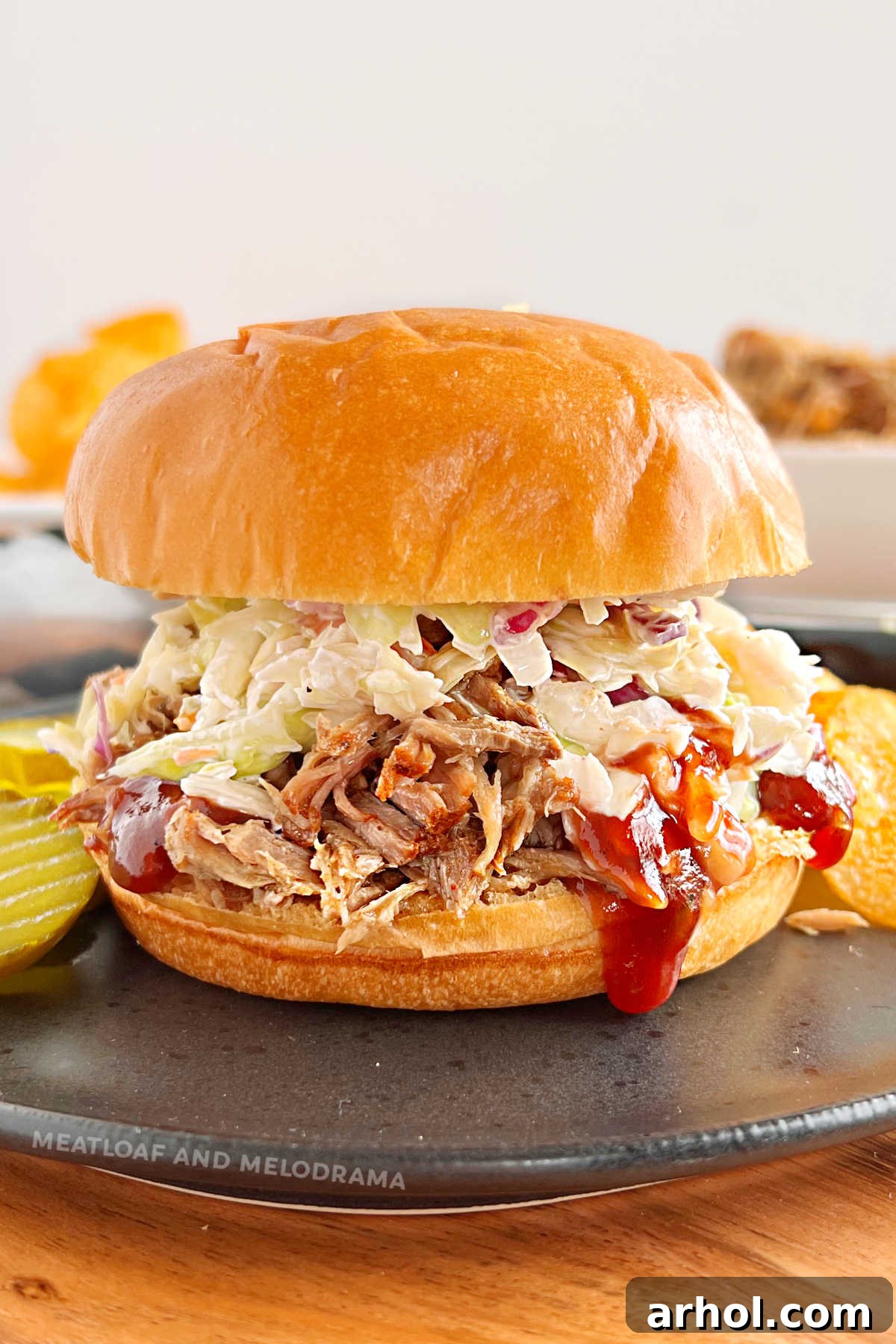 Instant Pot pulled pork sandwich with coleslaw and BBQ sauce on a black plate