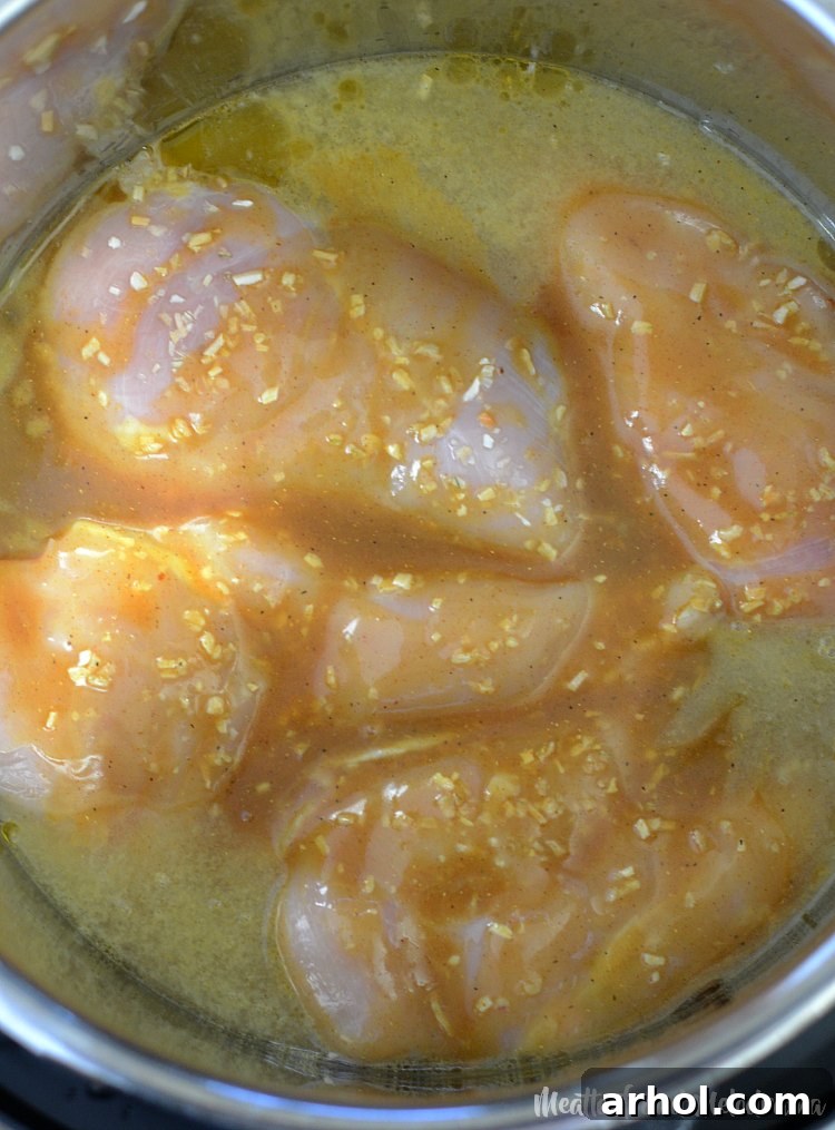Instant Pot honey mustard curry chicken simmering in the pot, sauce thickening.