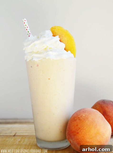 Creamy peach milkshake in a tall glass, garnished with fresh peach slices