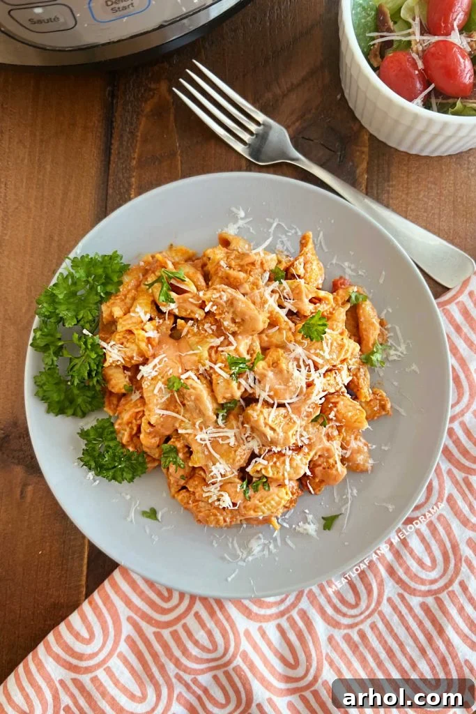 Instant Pot creamy chicken pasta with parsley and Parmesan cheese on the table, garnished and ready to serve