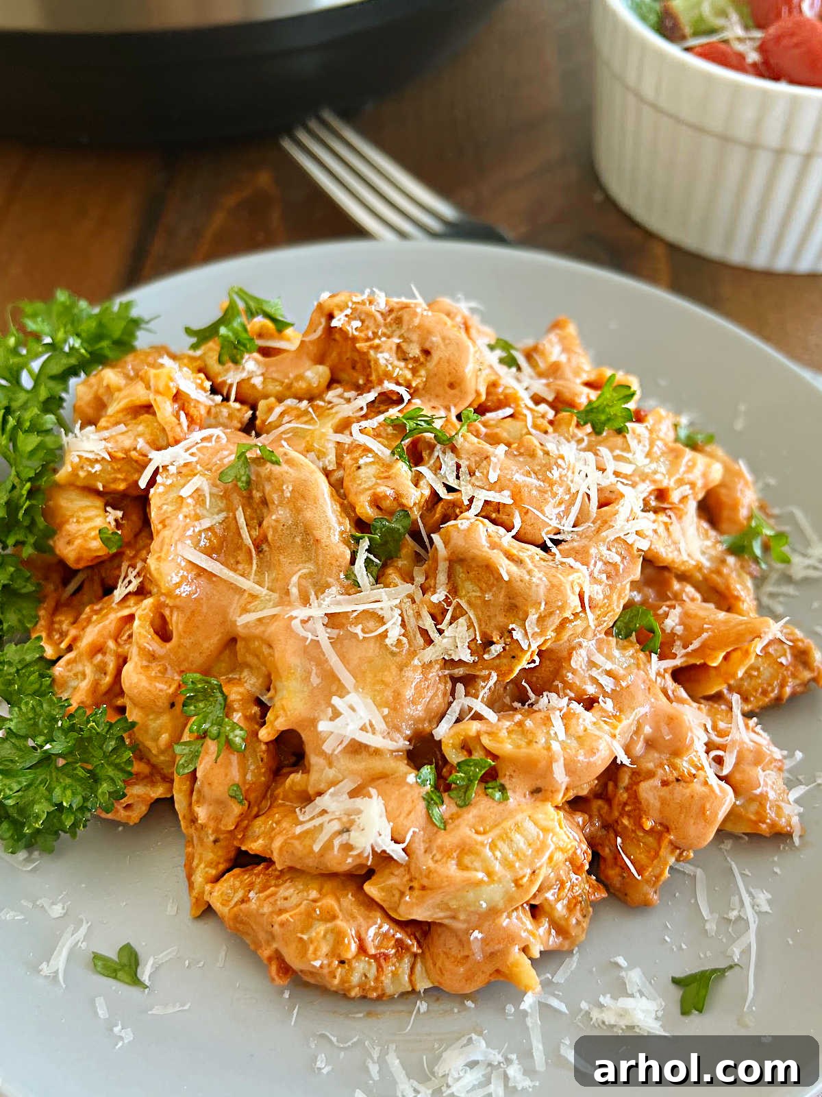 Plate of Instant Pot creamy chicken pasta with freshly grated Parmesan cheese and a sprinkle of parsley