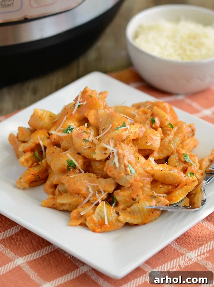 Instant Pot creamy chicken pasta with parmesan cheese on a white plate with fork