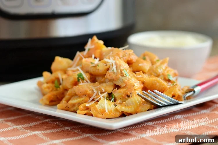 Instant Pot creamy chicken pasta shells on white plate with a fork, ready to be enjoyed