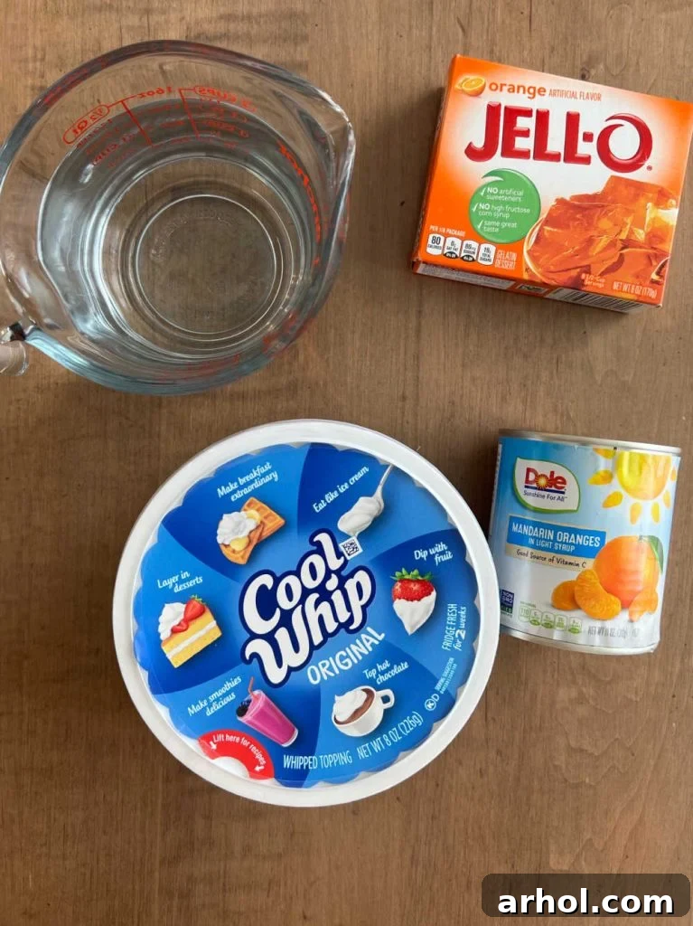 The four simple ingredients for orange Jello salad: Cool Whip, orange Jello mix, mandarin oranges, and water.