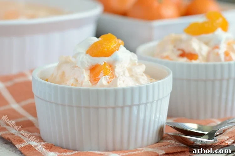 A festive close-up of orange jello fruit salad with mandarin oranges in a serving bowl.
