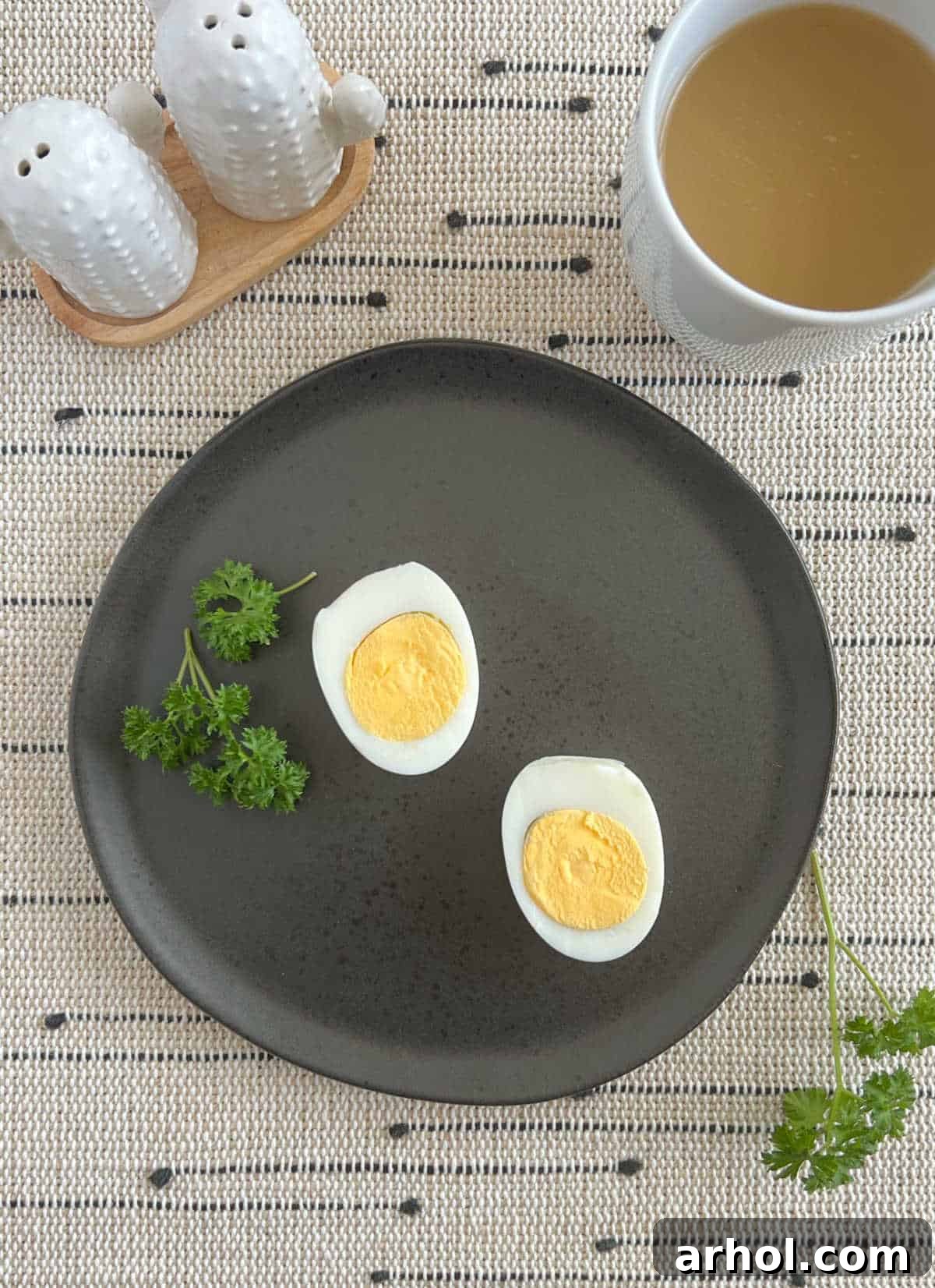Two perfectly cooked Instant Pot hard boiled eggs, sliced, on a black plate.