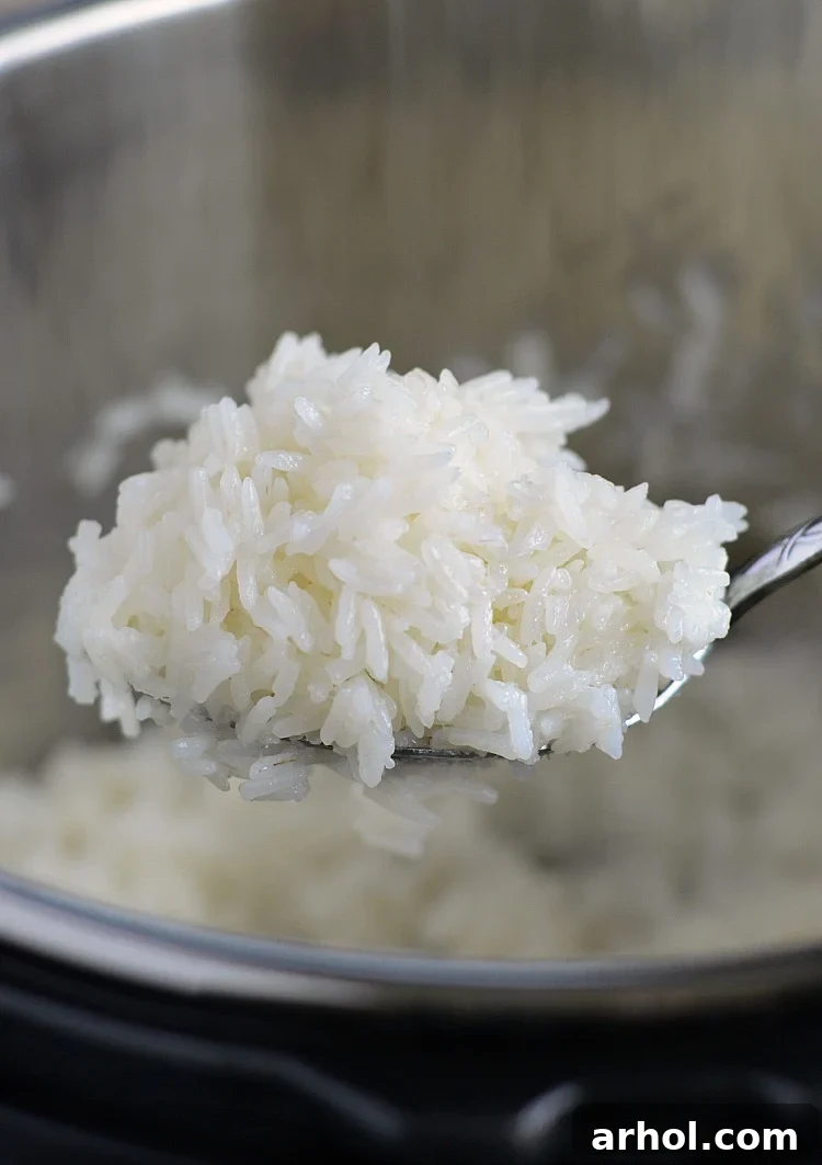 Fluffy Instant Pot jasmine rice being scooped onto a spoon, showing its perfect texture.