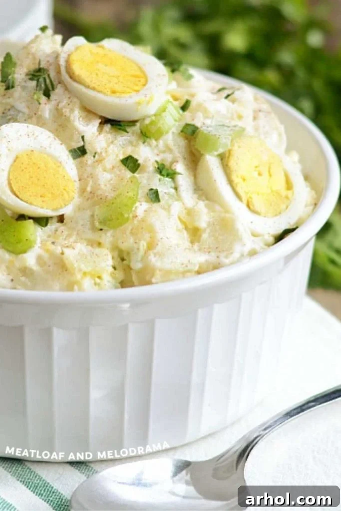 Effortless Instant Pot Potato Salad 2 A close-up view of creamy Instant Pot potato salad, generously topped with neatly sliced hard-boiled eggs and a delicate sprinkle of smoked paprika, served in an elegant white bowl.