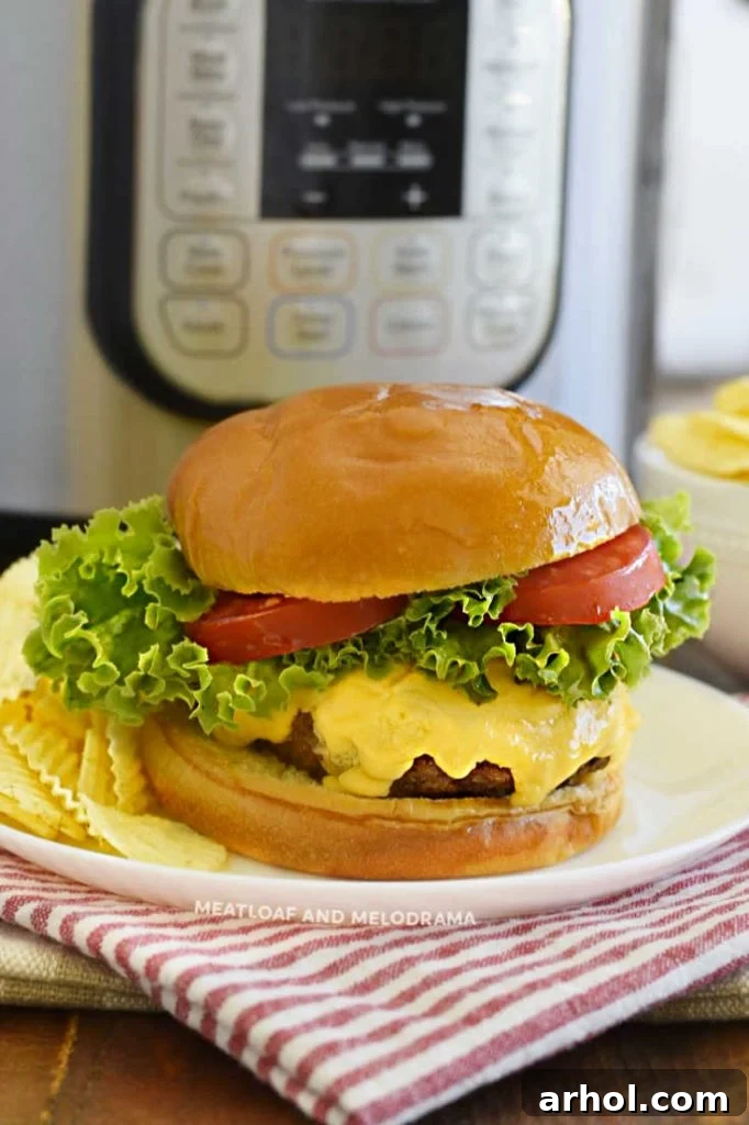 A perfectly cooked cheeseburger with crisp lettuce and ripe tomatoes on a plate, with an Instant Pot visible in the background, signaling an easy meal.