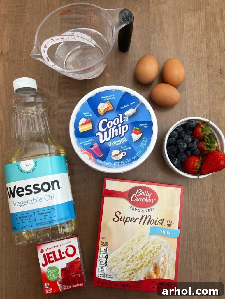 Collection of key ingredients for a red, white, and blue poke cake, including white cake mix, strawberry jello, oil, cool whip, eggs, water, and fresh fruit on a rustic wooden surface.