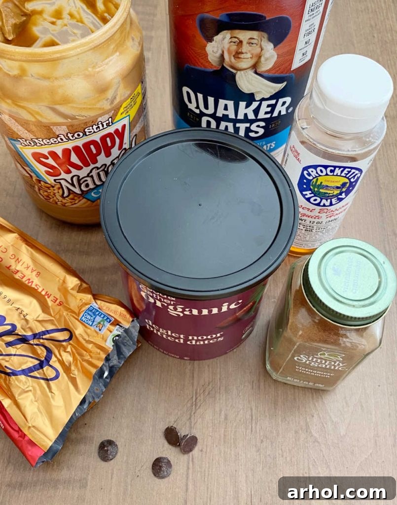Various ingredients for energy balls, including rolled oats, peanut butter, honey, cinnamon, dates, and chocolate chips, laid out on a wooden table.